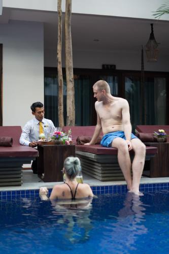 a man sitting in a swimming pool next to a woman at Golden Temple Retreat in Siem Reap