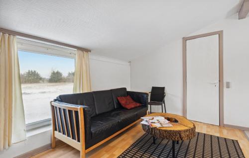 a living room with a black leather couch and a table at 2 Bedroom Nice Apartment In Ringkøbing in Ringkøbing