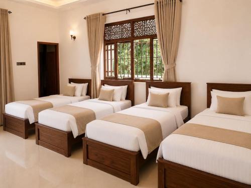 three beds in a room with a window at Crescent Villa in Kalutara