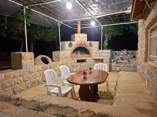 a patio with a table and chairs and an oven at Beit El Jabal in Al Mudayrij