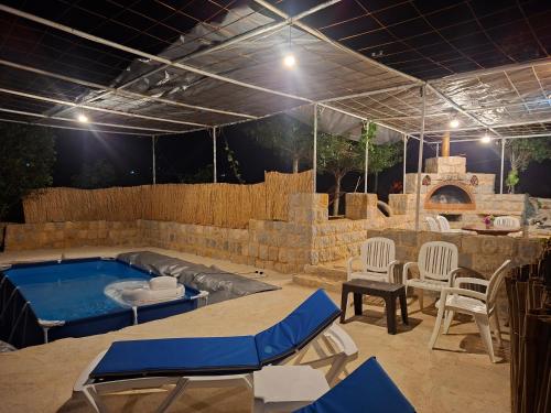 a patio with a hot tub and a table and chairs at Beit El Jabal in Al Mudayrij