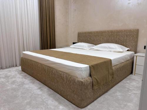 a bedroom with a large bed with white sheets and pillows at ASR Plaza in Jizzax