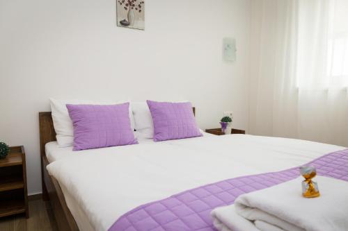 a bedroom with a large bed with purple pillows at Aqualiget-Apartmanház E-Car plug-in point Szeged in Szeged