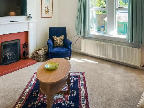 a living room with a table and a chair and a fireplace at Rose Cottage - Uk52178 in Leven