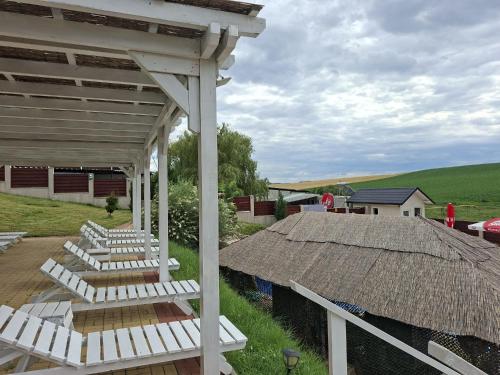 a group of white lounges on a porch with a roof at La Hacienda in Cheţani