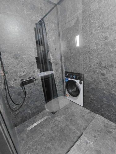 a shower with a washing machine in a bathroom at B&L Apartmani in Sutomore