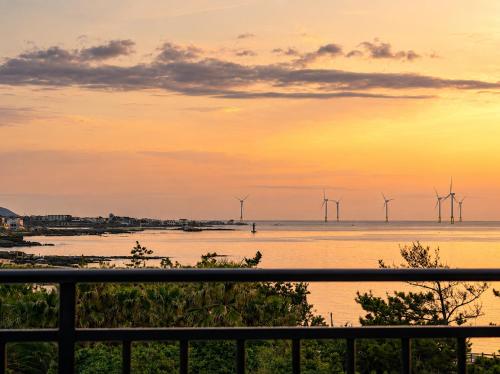 a group of windmills in the water at sunset at 오후여섯시펜션 in Jeju