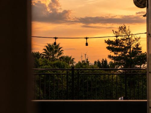 a view of a sunset from a balcony with a fence at 오후여섯시펜션 in Jeju