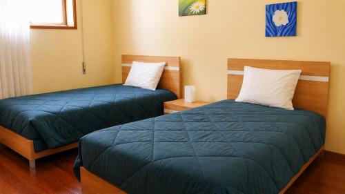 two beds in a room with blue sheets at Pôr do Sol in Vila Nova de Gaia