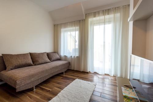 a living room with a couch and a large window at Aqualiget-Apartmanház E-Car plug-in point Szeged in Szeged
