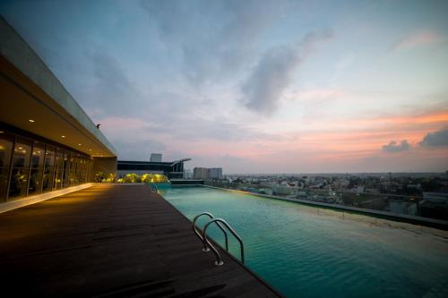 a swimming pool on the roof of a building with a sunset at Citadines OMR Chennai in Chennai