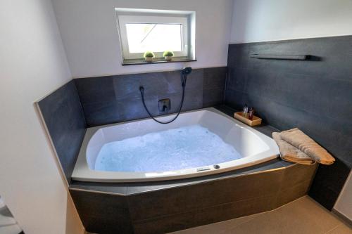 a large bath tub in a bathroom with a window at Ferienwohnnung EifelPanorama Berk in Dahlem