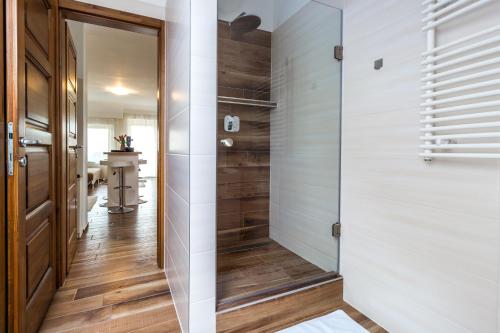 a walk in shower in a bathroom with a glass door at Aqualiget-Apartmanház E-Car plug-in point Szeged in Szeged