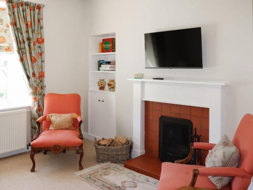 a living room with a fireplace with a tv above it at Heather Cottage - Uk52177 in Leven