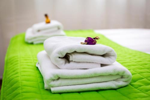 a stack of white towels on a green blanket at Aqualiget-Apartmanház in Szeged