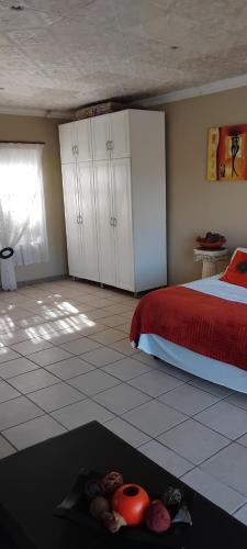 a bedroom with a bed with a red bedspread and a window at RestZone Healing Guest Suite in Pietermaritzburg
