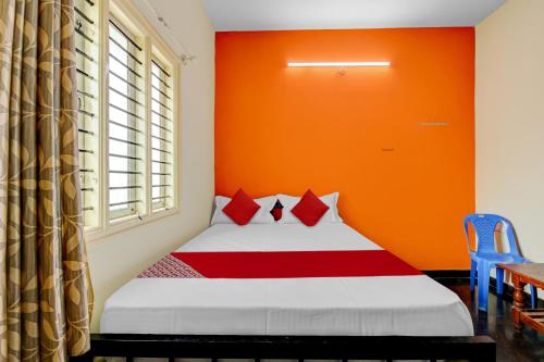 a bedroom with a bed with an orange wall at SPOT ON Ganesh in Kaglipur