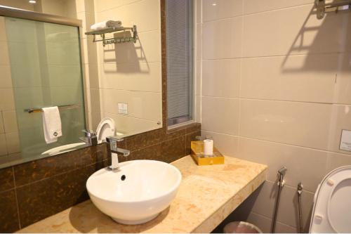 a bathroom with a sink and a mirror and a toilet at Greenmont Hotel & Apartment in Bandar Seri Begawan