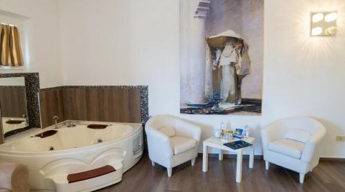 a bathroom with a tub and two chairs and a painting at Essence Isola d'Elba - Le Picchiaie Resort in Portoferraio