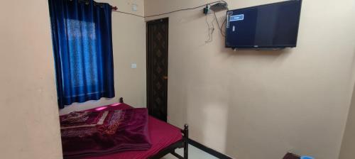 a room with a bed and a tv on a wall at Yamuna rooms and dormitory in Ooty
