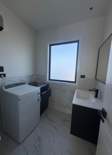 a white bathroom with a sink and a window at 2 Bedroom Granny Flat in Runciman