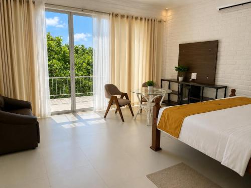 a bedroom with a bed and a table and a window at Dutch Bay Resort & Spa in Kalpitiya