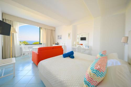 a bedroom with a white bed and a red couch at Paradiso Terme Resort & SPA con 5 piscine termali in Forio d'Ischia