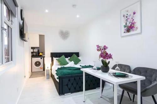 a small apartment with a bed and a table and chairs at Studio - Sleeps 2 - 5 Min to Trains - Parking in Thornton Heath