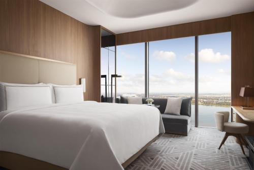 a bedroom with a large white bed and a desk at Shangri-La Phnom Penh in Phnom Penh