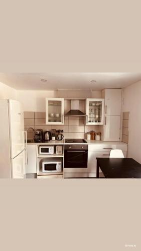 a large kitchen with white cabinets and appliances at Cham Crest in Friern Barnet