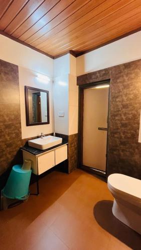 a bathroom with a sink and a toilet and a mirror at Gavadana Resort Coorg in Madikeri