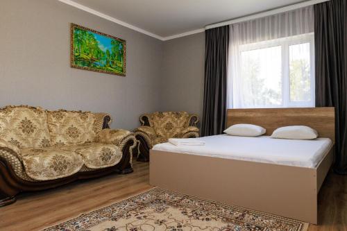 a bedroom with a bed and two chairs and a window at Hotel Дар-Ай in Kostanay