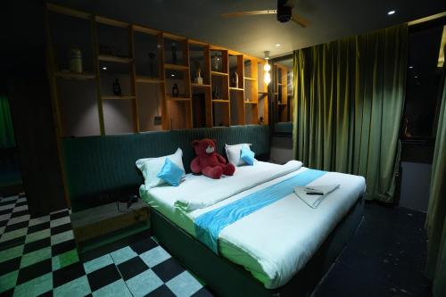 a teddy bear sitting on a bed in a room at Roots in Pune