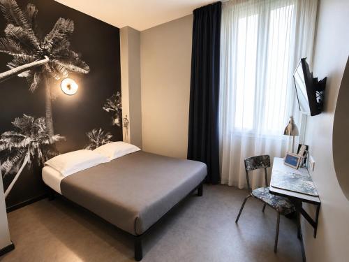 ein Schlafzimmer mit Bett, Schreibtisch und Fenster in der Unterkunft Hotel Alnea in Cannes