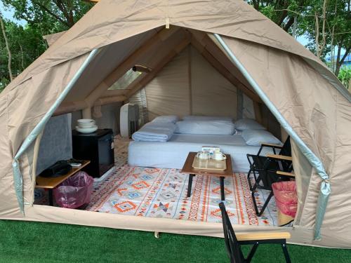 a tent with a bed and a table in it at Riverside Glamping Resort Kanchanaburi in Kanchanaburi City