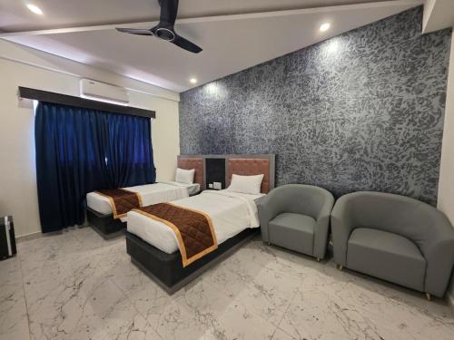a bedroom with two beds and a couch and chairs at Hotel Srs Manor in Hārohalli