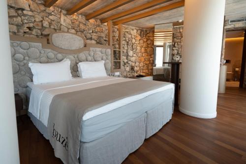 a large bed in a room with a stone wall at Buzë Boutique Hotel in Sarandë