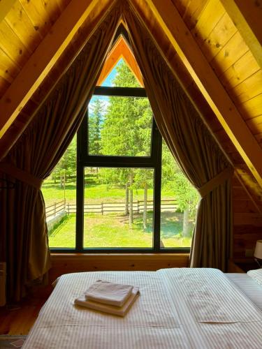 a bedroom with a bed and a large window at A-frame Durmitor in Žabljak