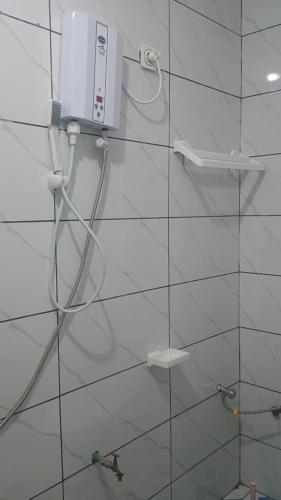 a white tiled bathroom with a shower with aitizer at Sky Blue Guest House Buea in Buea