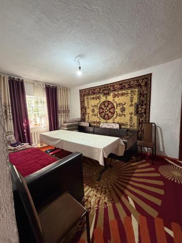 a bedroom with a bed and a couch and a rug at Felt painting in Kara-Suu