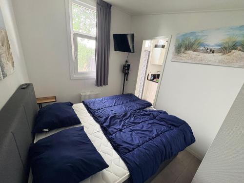 una camera da letto con un letto blu e bianco e una finestra di Heimathafen a Lathum