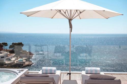 a patio with an umbrella and chairs and a swimming pool at The Donna Portals in Portals Nous