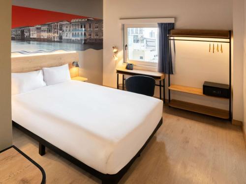 a hotel room with a white bed and a desk at Ibis Styles El Malecon Guayaquil in Guayaquil
