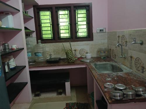 a kitchen with a sink and a counter with windows at PR Home Stay in Tiruvidaimarudūr