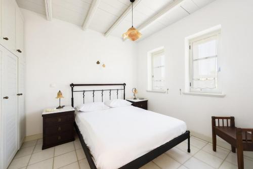 a white bedroom with a bed and two windows at Aurora by Mediterra in Isterni