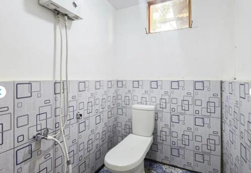 a bathroom with a white toilet and a shower at Cozzy Villa TB & Outbond in Riunggunung