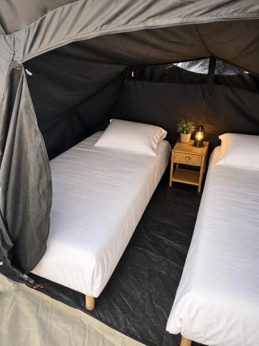 two beds in a tent with a side table at Glamping - accès JACUZZI et SAUNA in Boulogne-sur-Mer