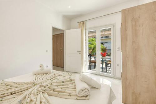 a white bedroom with a large bed and a window at Jimmy's by the beach ipsos in Ipsos