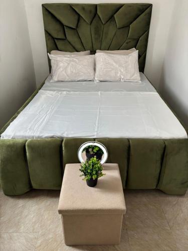 a bedroom with a large bed with a plant on a table at Maison BA à Ouenzé in Brazzaville