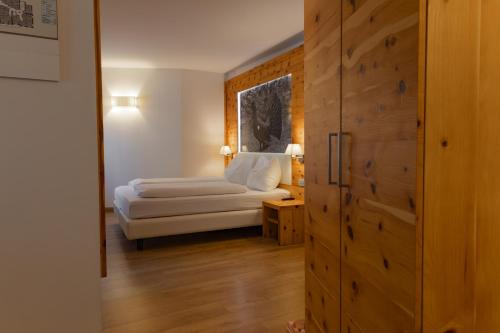 a bedroom with a bed and a wooden door at Active Hotel Pineta in Baselga di Pinè